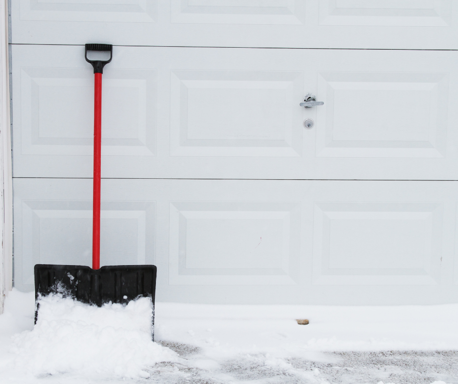 shovel leaning on a garage door. snow covered ground